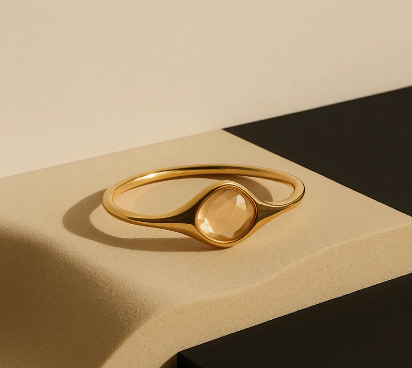 Bracciale rigido in argento placcato oro 18KT con quarzo champagne, su spigolo di pietra color sabbia